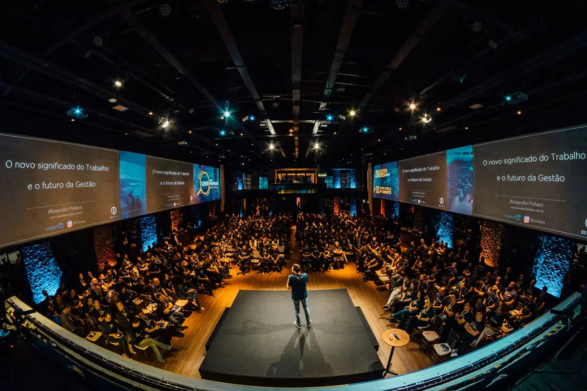 Speaker presenting on stage to a large corporate audience