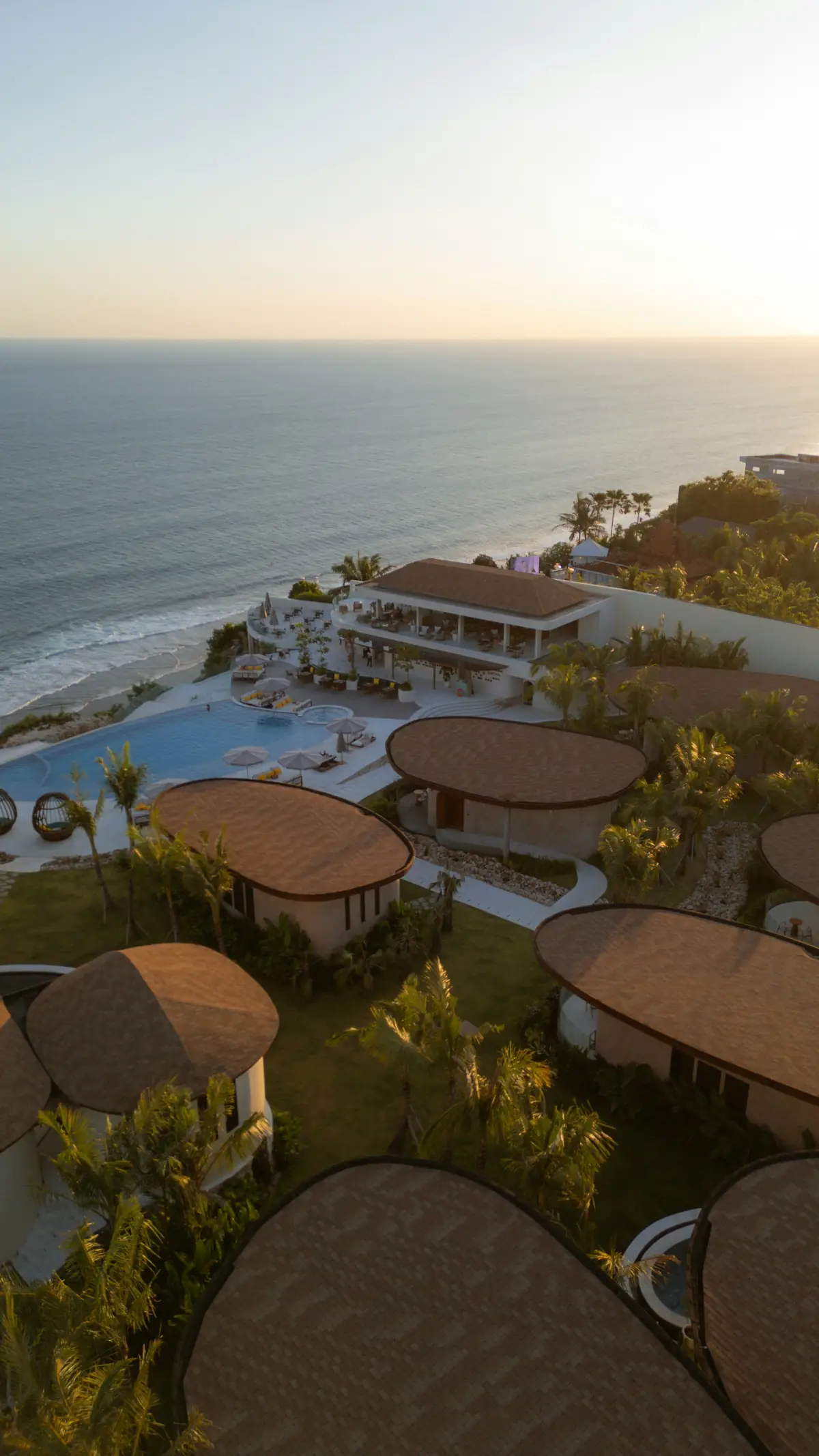 Beachfront resort villas and a pool overlooking the ocean at sunset